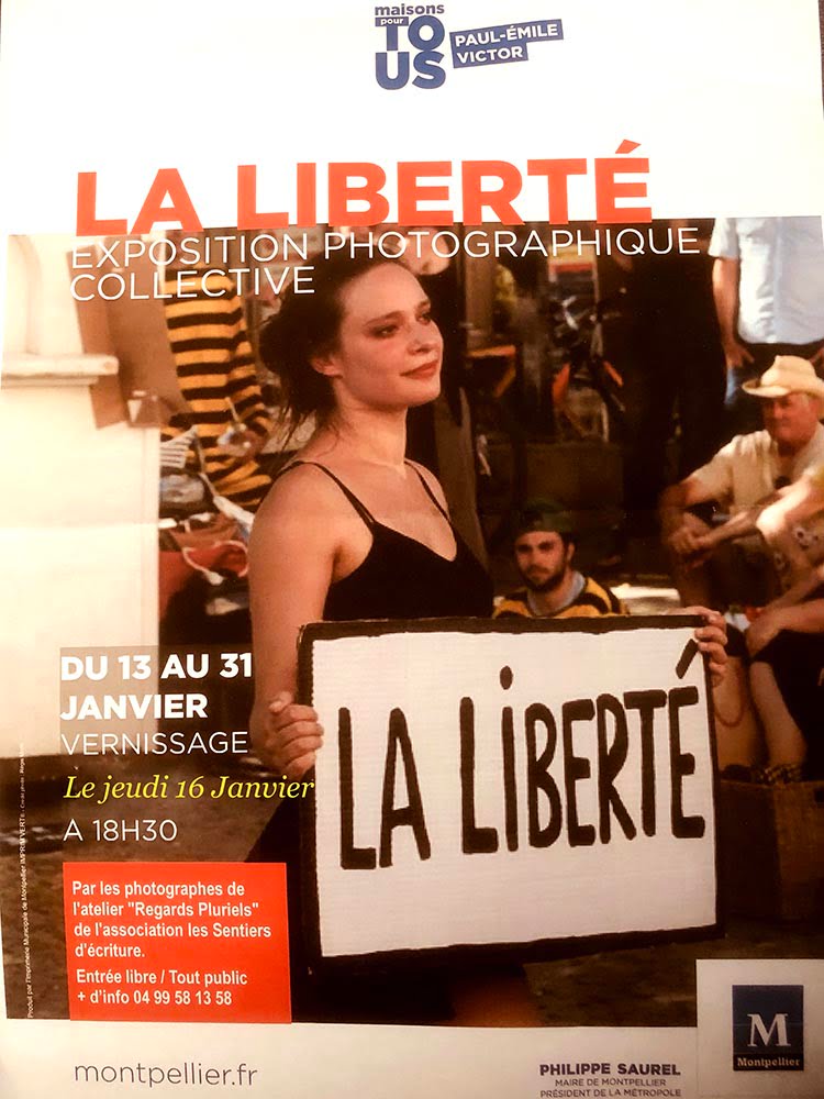 Affiche expo photo sur la liberté - Une fille qui tiens une pancarte avec les mots "La liberté" écrit dessus.